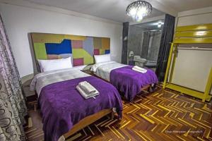 Habitación de hotel con 2 camas y mantas moradas en Casa valicha, en Cusco