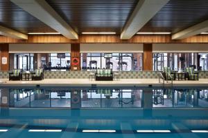 a swimming pool in a building with chairs and tables at Delta Hotels by Marriott Prince Edward in Charlottetown