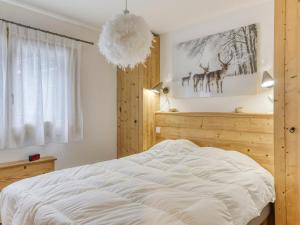 a bedroom with a large white bed and a chandelier at Appartement rénové 2 chambres, proche centre Megève, lumineux, parking, animaux acceptés - FR-1-453-296 in Megève
