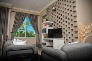sala de estar con 2 sillas y TV en Hotel Kingdom Appartments, en Mwanza