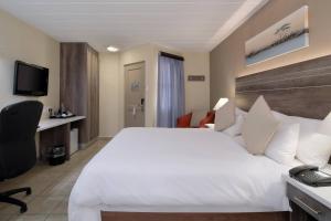 ポロクワネにあるProtea Hotel by Marriott Polokwane Landmarkの白い大型ベッド1台、デスクが備わる客室です。