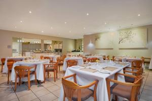 uma sala de jantar com mesas e cadeiras brancas em Protea Hotel by Marriott Polokwane Landmark em Polokwane