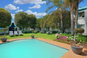 a swimming pool in a yard with palm trees at Protea Hotel by Marriott Polokwane Landmark in Polokwane