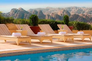 a group of four lounge chairs next to a pool at Petra Marriott Hotel in Wadi Musa