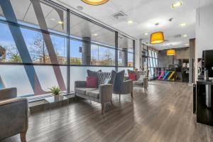 a lobby with couches and chairs and large windows at Roomzzz Leeds City West in Leeds