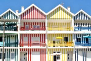 a row of colorful houses with chairs and an umbrella at Querido, Vamos de Férias! in Vagos