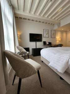 a bedroom with a bed and two chairs and a television at Hotel Grand Canal in Delft