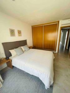 a bedroom with a large white bed and a wooden cabinet at Attic apartment in old town in Denia