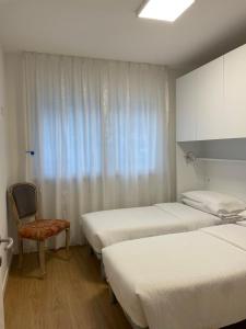 a room with two beds and a chair and a window at HOLIDAY APARTMENTS GIULIA - Blue in Pietramurata