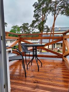 a wooden balcony with a table and chairs on a deck at "Hel" Wieniec Zdrój in Włocławek