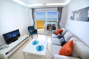 a living room with a white couch and a tv at Las Gemelas Apartments in La Manga del Mar Menor