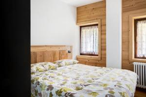 a bedroom with a bed and two windows at Alta Valle Maira B in Acceglio