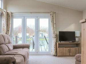 a living room with a tv and a sliding glass door at Tiptoes Lodge in Carnforth