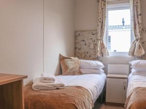 a small bedroom with a bed with towels on it at Tiptoes Lodge in Carnforth