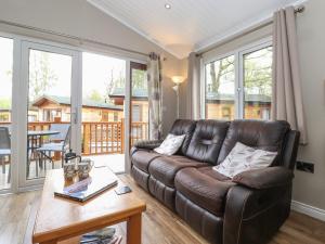 a living room with a leather couch and a table at 18 Crake Valley in Ulverston