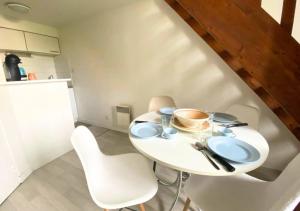 - une table blanche avec deux chaises et une tasse de café dans l'établissement Le Sainte-Croix - Poitiers Centre - La Conciergerie., à Poitiers