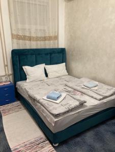 a bed with a blue headboard and two books on it at Sobe sa sopstvenim KUPATILOM Private rooms bathroom In CENTER in Novi Sad