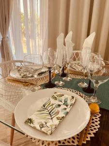a table with a plate and wine glasses on it at Casa Conforto Bilene in Vila Praia Do Bilene