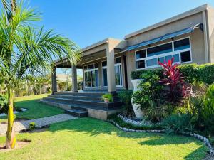 a house with a palm tree in front of it at Casa Conforto Bilene in Vila Praia Do Bilene