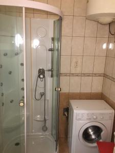 uma casa de banho com um chuveiro e uma máquina de lavar roupa em Cozy flat at Stadionok M station em Budapeste