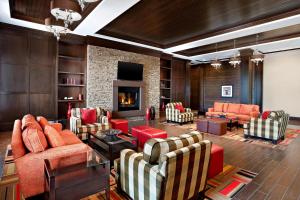 a living room with orange chairs and a fireplace at Four Points by Sheraton Edmonton Gateway in Edmonton