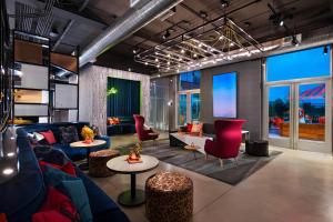 a living room with a blue couch and red chairs at Aloft San Antonio UTSA Area in San Antonio