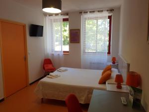 1 dormitorio con 1 cama y 2 sillas rojas en Résidence du Rougier en Camarès