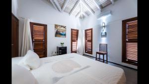 Schlafzimmer mit einem weißen Bett, einem Stuhl und Fenstern in der Unterkunft Beautiful Villa with pool near the beach for groups in Jan Thiel + 28 Fotos