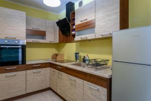 kuchnia z drewnianymi szafkami i białą lodówką w obiekcie Studio parking TV WiFi w Gdańsku