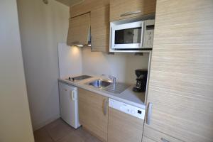 a small kitchen with a sink and a microwave at Studio Ève Résidence Naturiste Le Jardin D'Eden in Cap d'Agde