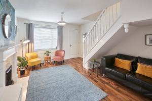 uma sala de estar com um sofá de couro preto e cadeiras em Host & Stay - Garden Cottage em Durham