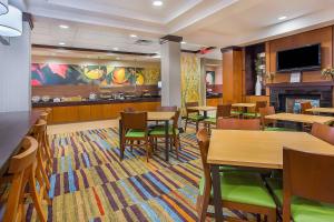 a restaurant with tables and chairs and a fireplace at Fairfield Inn & Suites Louisville East in Louisville