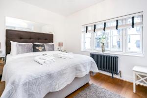 um quarto branco com uma cama grande e toalhas em Hidden gem in Covent Garden em Londres