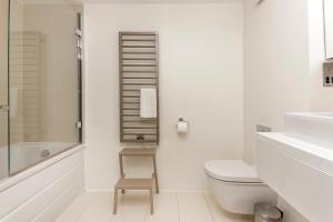 a white bathroom with a toilet and a chair in it at Hidden gem in Covent Garden in London