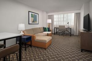 Residence Inn by Marriott Washington - DC/Foggy Bottom في واشنطن: غرفة معيشة مع أريكة ومكتب في غرفة الفندق