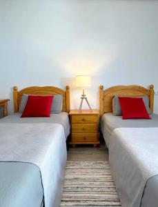 2 camas con almohadas rojas en una habitación en Holibai, Curuxa, Tranquilidad En El Casco Histórico De Baiona, en Baiona