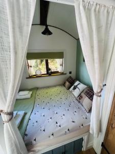 a bedroom with a bed with curtains and a window at Romantic Shepherd Hut with Optional Hot Tub in Snowdonia in Dolgellau