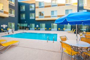 - une piscine avec une table, des chaises et un parasol dans l'établissement Fairfield Inn & Suites by Marriott San Antonio Brooks City Base, à San Antonio