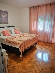 1 dormitorio con 1 cama con cortinas rosas y suelo de madera en Kuća JEKA, en Vrnjačka Banja