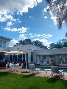 a house with chairs and an umbrella and a pool at Brooklyn Place in Pretoria
