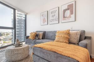 ein Wohnzimmer mit einem grauen Sofa und einem großen Fenster in der Unterkunft Mega Style Apartments Bella in Melbourne