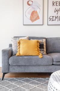 ein graues Sofa mit gelbem Kissen im Wohnzimmer in der Unterkunft Mega Style Apartments Bella in Melbourne