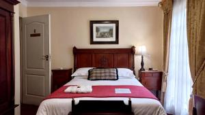um quarto com uma cama grande e um cobertor vermelho em Brooklyn Place em Pretoria