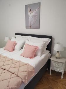 um quarto com uma cama com almofadas cor-de-rosa e brancas em Kuća JEKA em Vrnjačka Banja