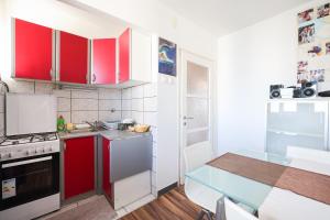 a small kitchen with red cabinets and a table at Apartman Cruiser in Zadar