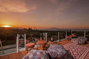 un balcón con sillas, mesas y una puesta de sol en Farao Villa en Kypseli