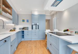 a kitchen with blue cabinets and white counter tops at The Old Bakery in Newlyn