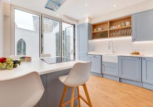 a kitchen with white counters and white chairs at The Old Bakery in Newlyn