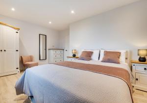 a white bedroom with a large bed and a chair at 2 North Bank in Amble