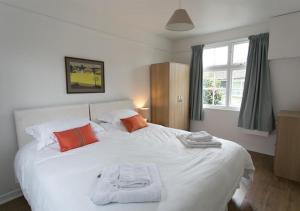 ein Schlafzimmer mit einem großen weißen Bett mit orangefarbenen Kissen in der Unterkunft Old Mill Cottage in Gweek